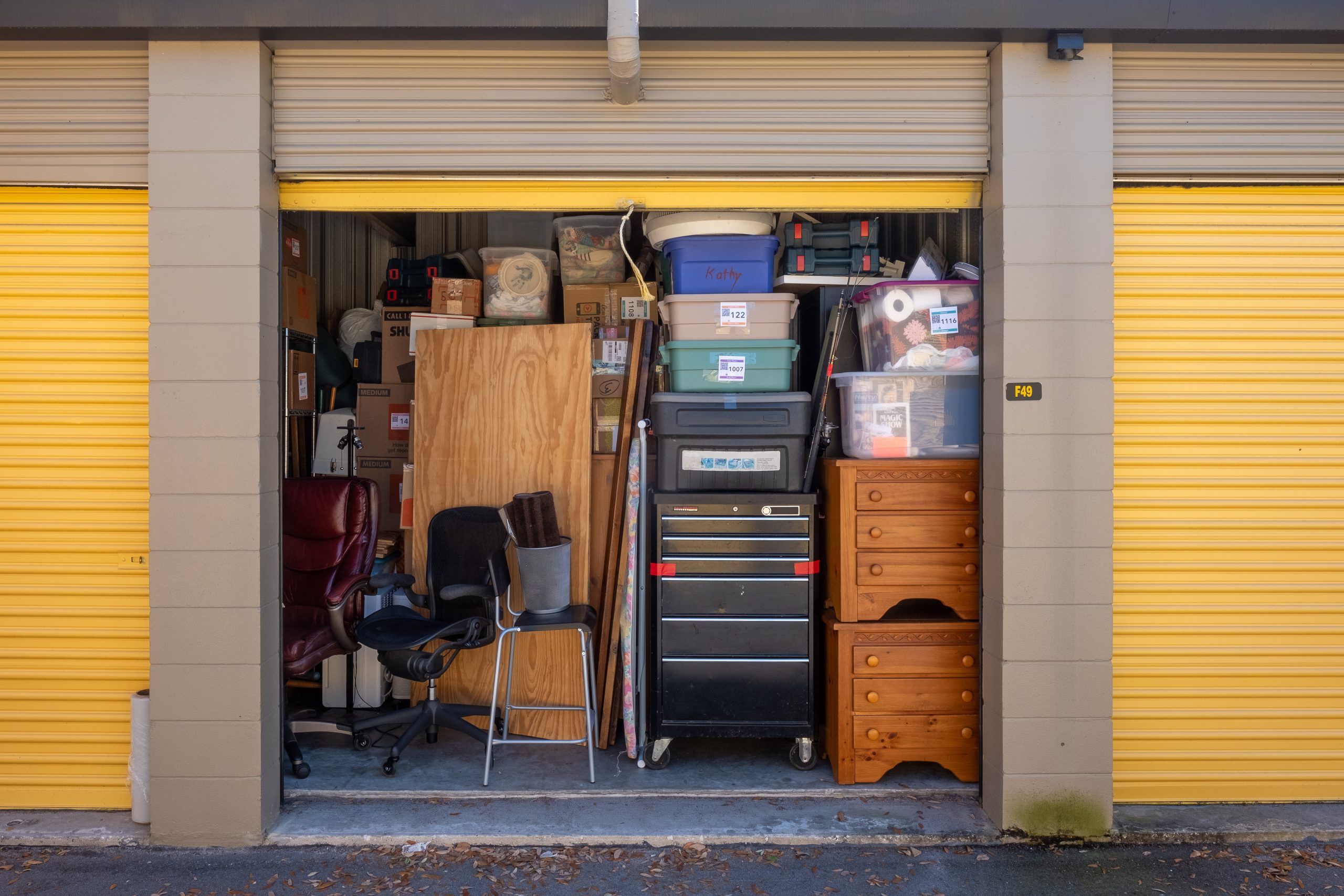 Storage unit packed full of totes, furniture, shop benches, chairs, cardboard boxes and more.